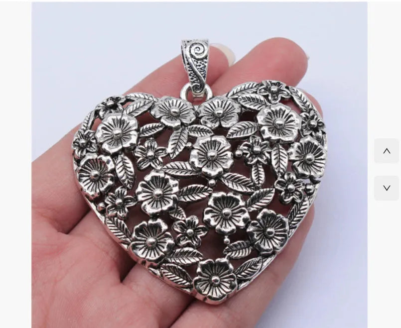 Close-up of a hollow flower love pendant in ancient silver colour, showing its detailed openwork design.
