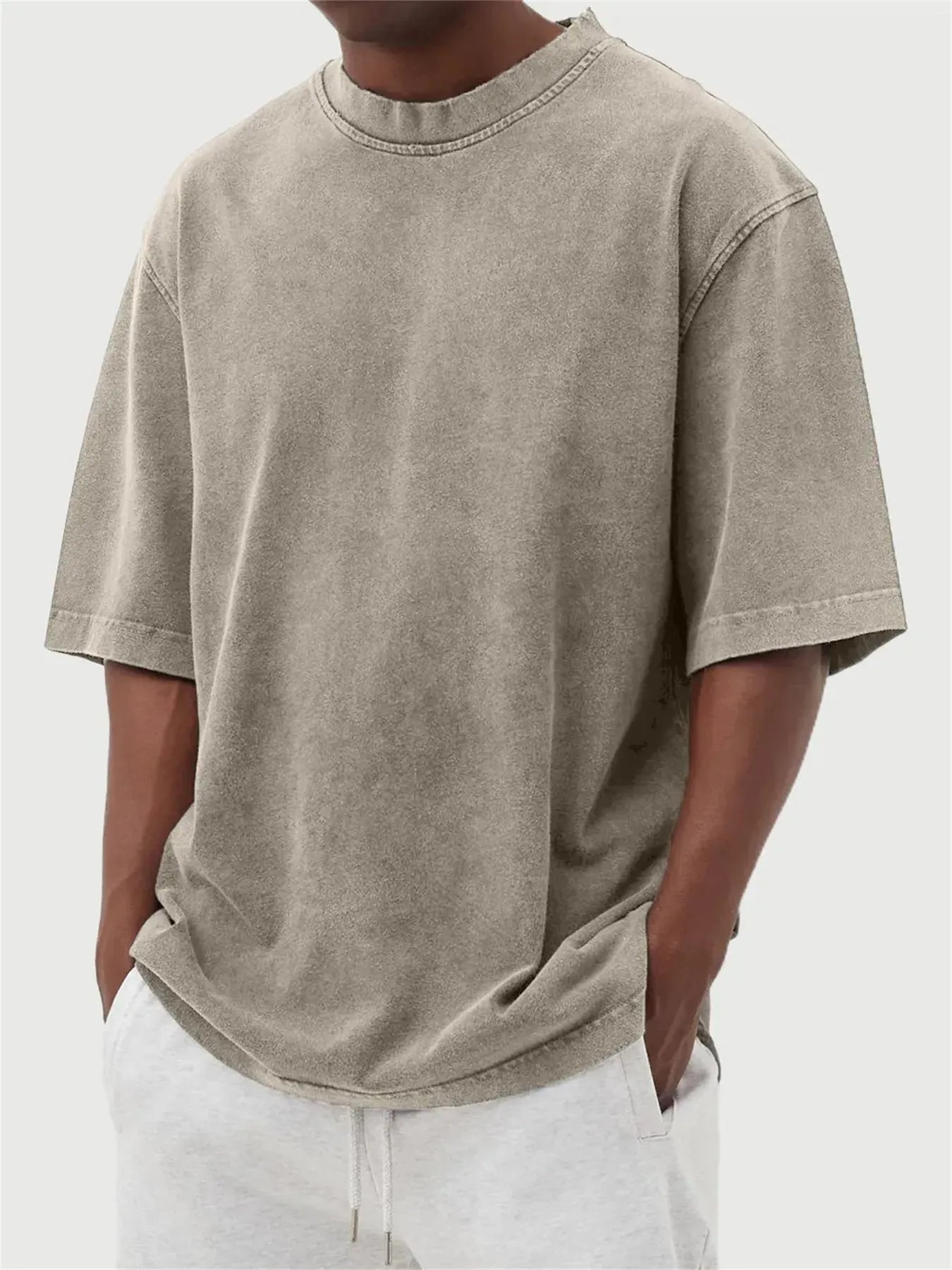 Man wearing a loose-fit, stone-washed polyester T-shirt in a solid colour with a distressed finish.