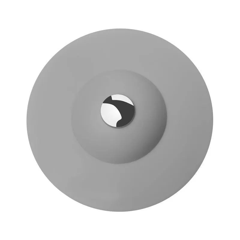 UFO-style silicone press sink drain cover in blue on a white basin, modern minimalist design