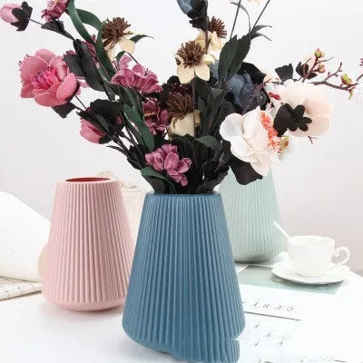 Blue melamine plastic decorative flower vase on a wooden desktop.