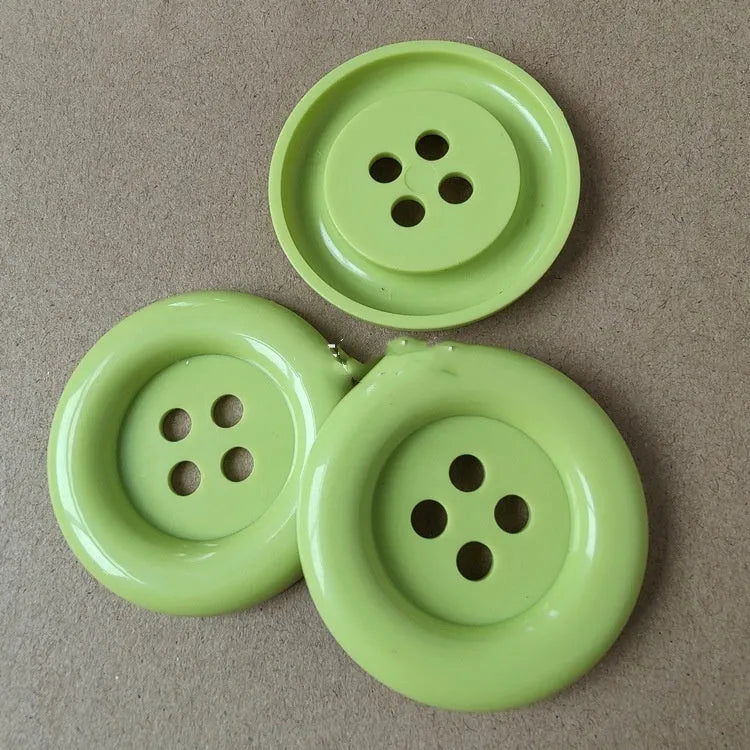 Assortment of oversized round plastic buttons in multiple colours with four stitching holes.