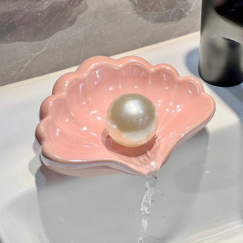 White or pink plastic shell-shaped soap dish for bathroom use.