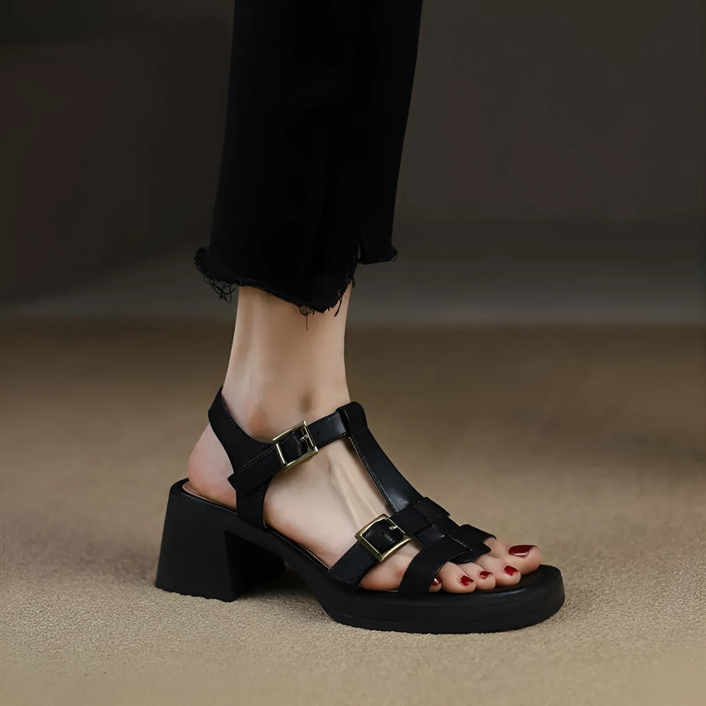 Women's black retro sandals with T-shaped buckle, chunky heel, and square open toe on a plain background.