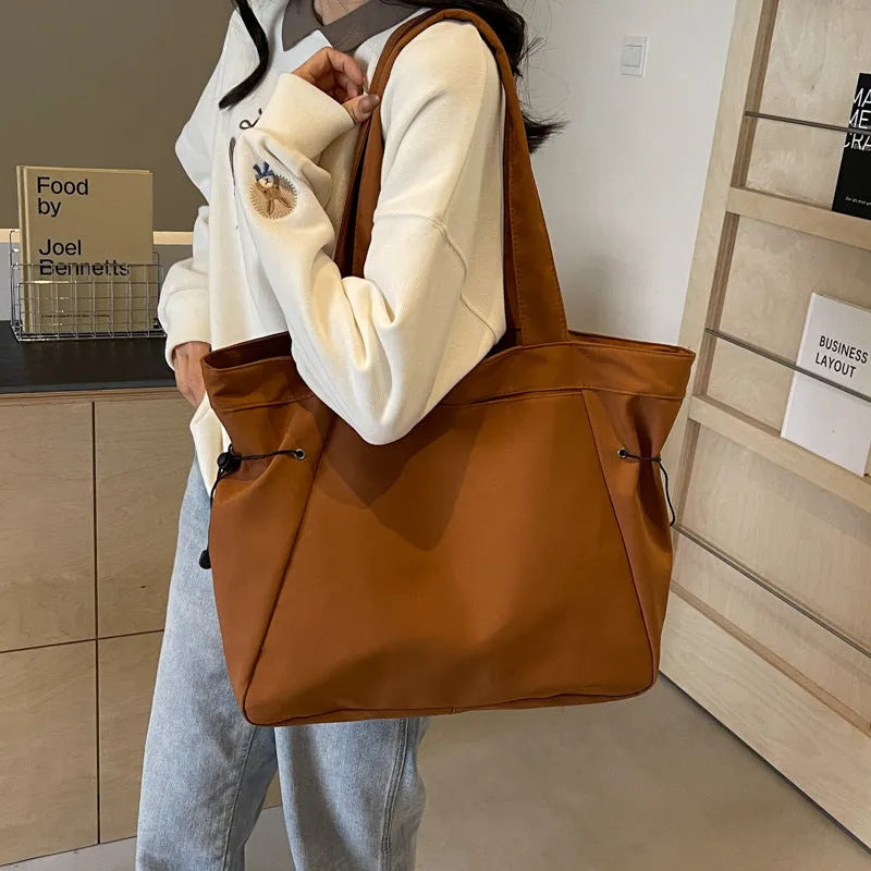 A foldable Oxford cloth commuter shoulder tote bag shown in one of five colours: black, brown, dark gray, light gray, or purple.