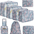 Eight cubic travel packing bags in various colours including beige, black, pink leopard print, and white pink stripes