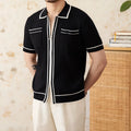 Man wearing a slim fit black knitted polo shirt with a lapel collar and short sleeves.
