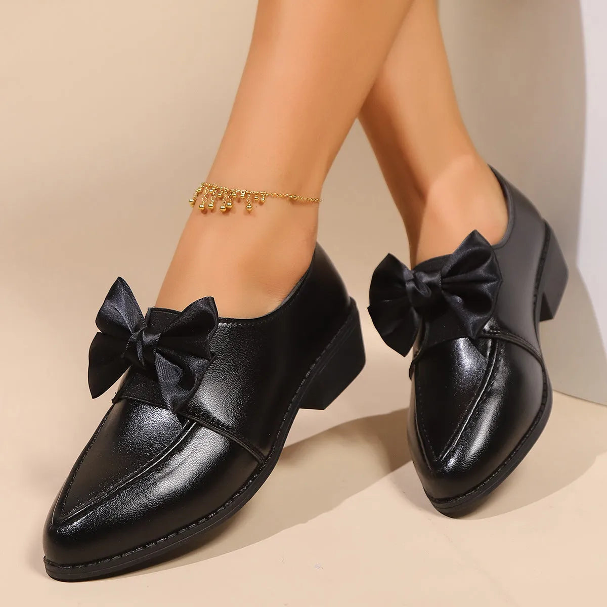 Women's brown slip-on flat shoes with a large bow decoration on the pointed toe.