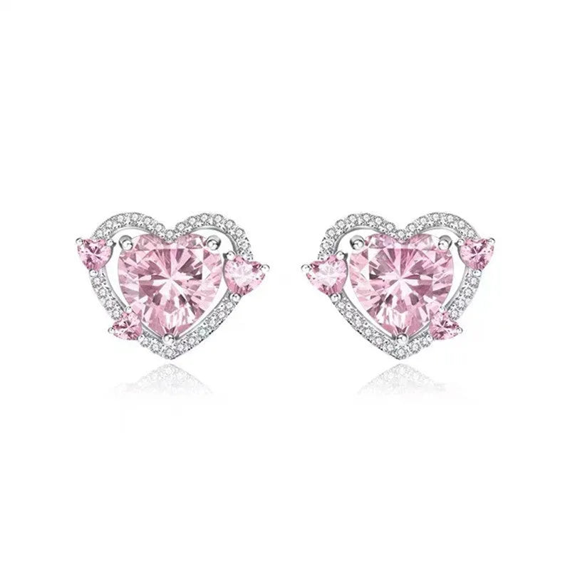 A pair of small white gold coloured heart shaped stud earrings for women on a jewellery card.