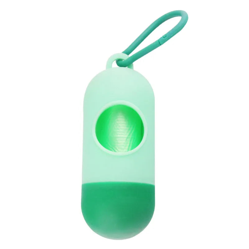 A compact black dog poop bag holder with a side hook and Velcro strap, shown next to a roll of waste bags.