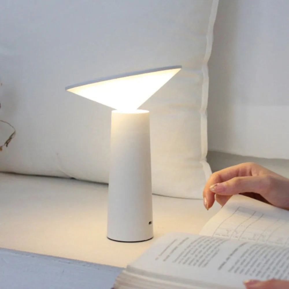 Black USB rechargeable LED desk lamp with touch sensor on a wooden desk, showing its adjustable lamp head.