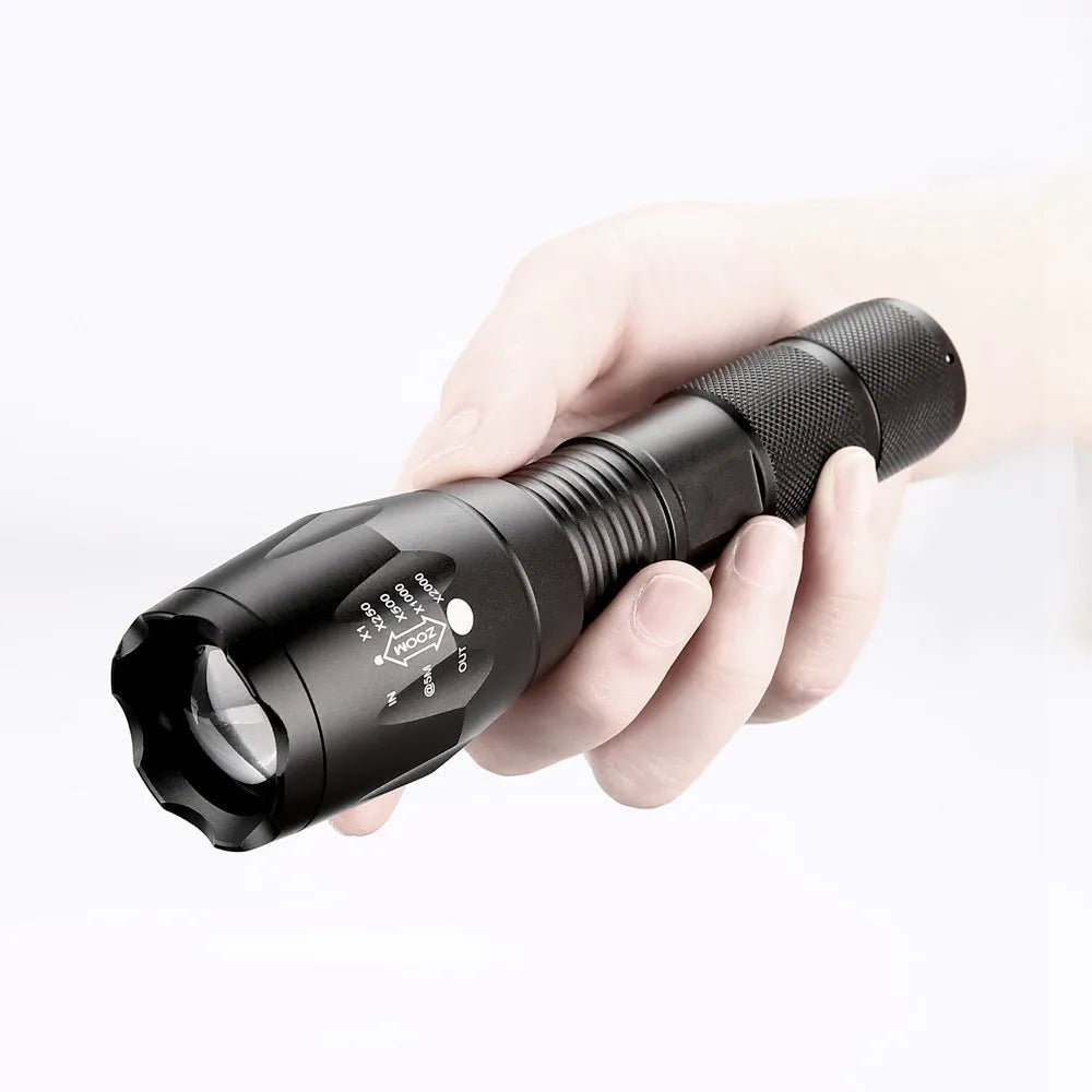 Black aluminum alloy zoom flashlight with adjustable head for focus, shown with beam reaching into distance.