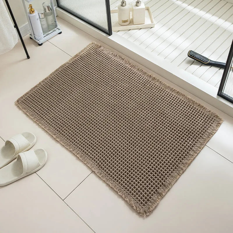 A square, checkered-pattern absorbent bathroom floor mat with a non-slip backing, shown in a neutral colour.