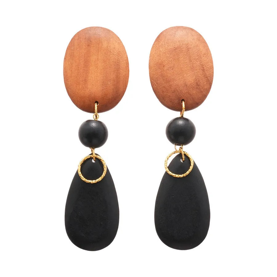 Close-up of handmade wooden elliptical earrings in silver, brown, and black colours on a retro-style background.