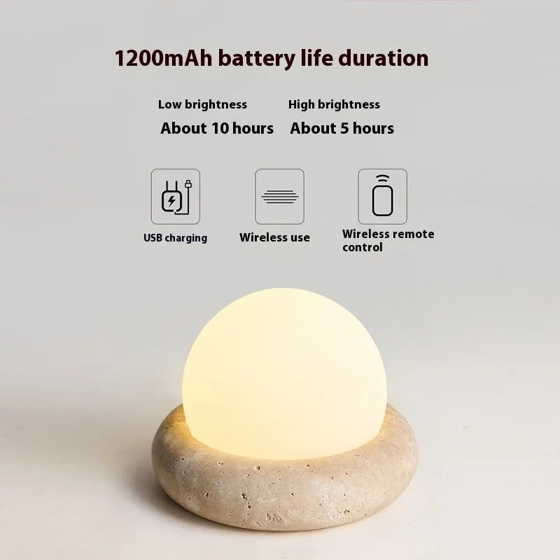 Cream coloured round rechargeable remote control night light on a bedside table.