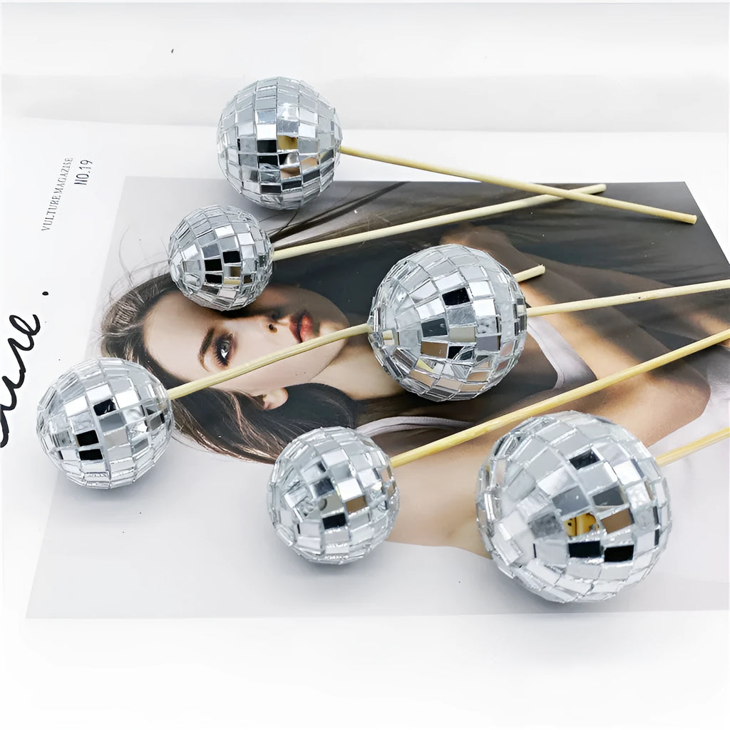 Glass disco ball cake decoration with wooden stick in various sizes on a birthday cake.