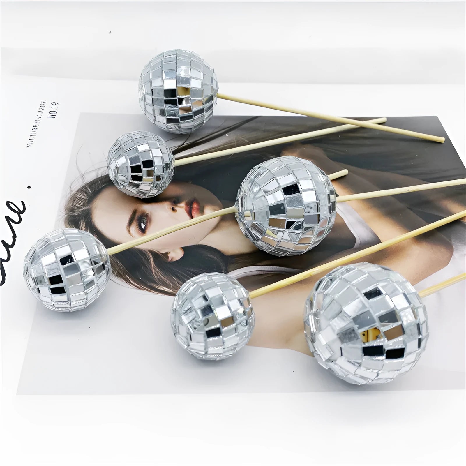 Glass disco ball cake decoration with wooden stick in various sizes on a birthday cake.