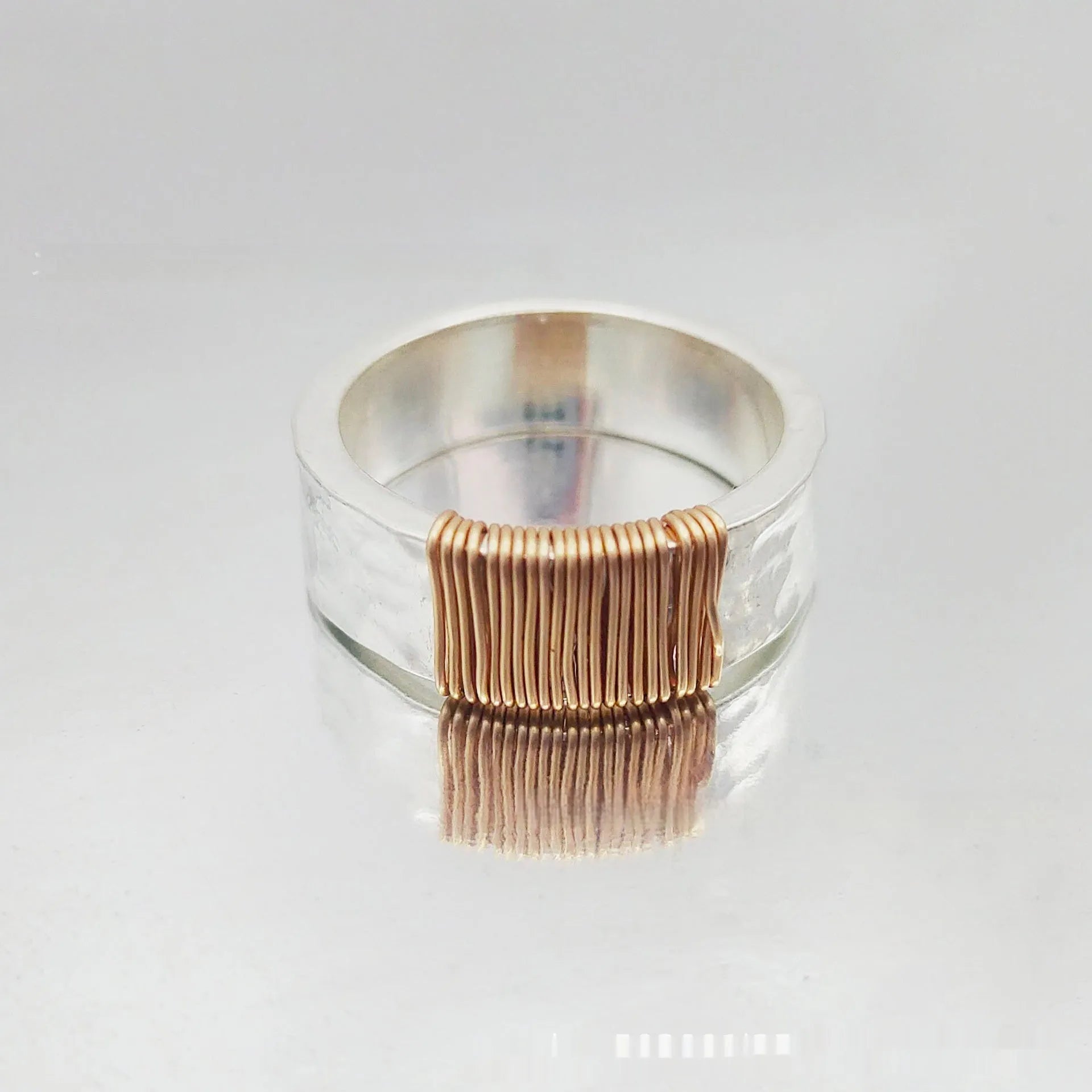 Silver golden geometric copper bracelet with an irregular coil and wide face ring design.
