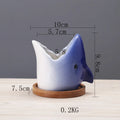 Creative cartoon ceramic succulent pot with drainage hole, blue colour, on a desk with a small succulent plant.