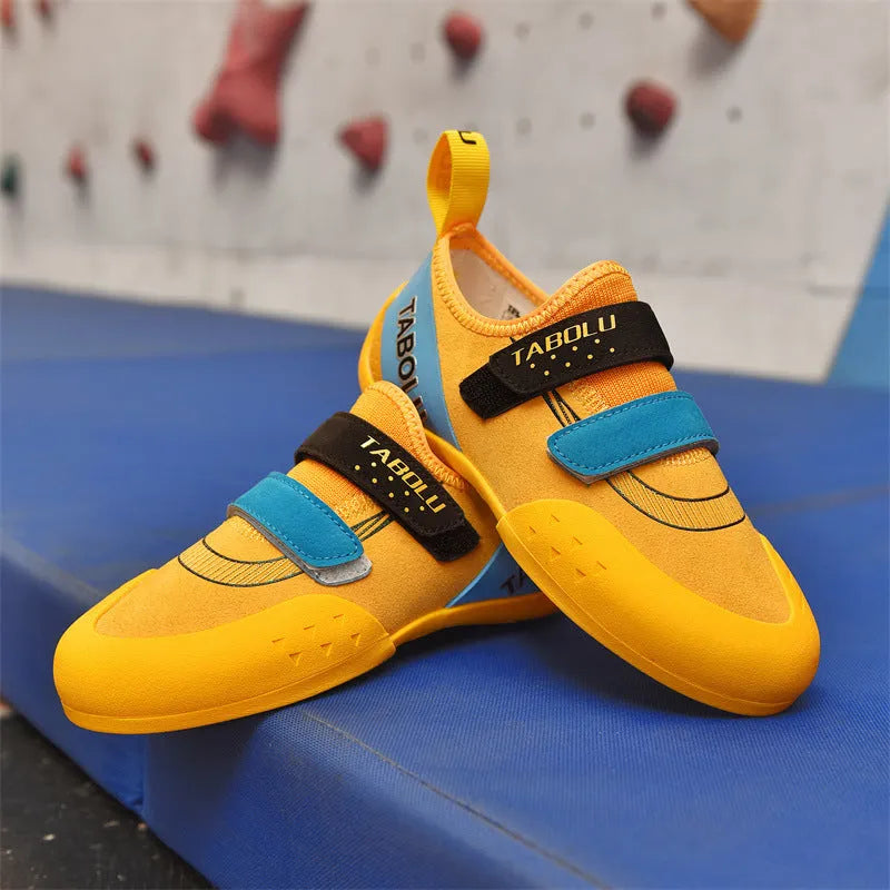Beginner rock climbing shoes with Velcro straps and a coloured rubber sole on a climbing hold.