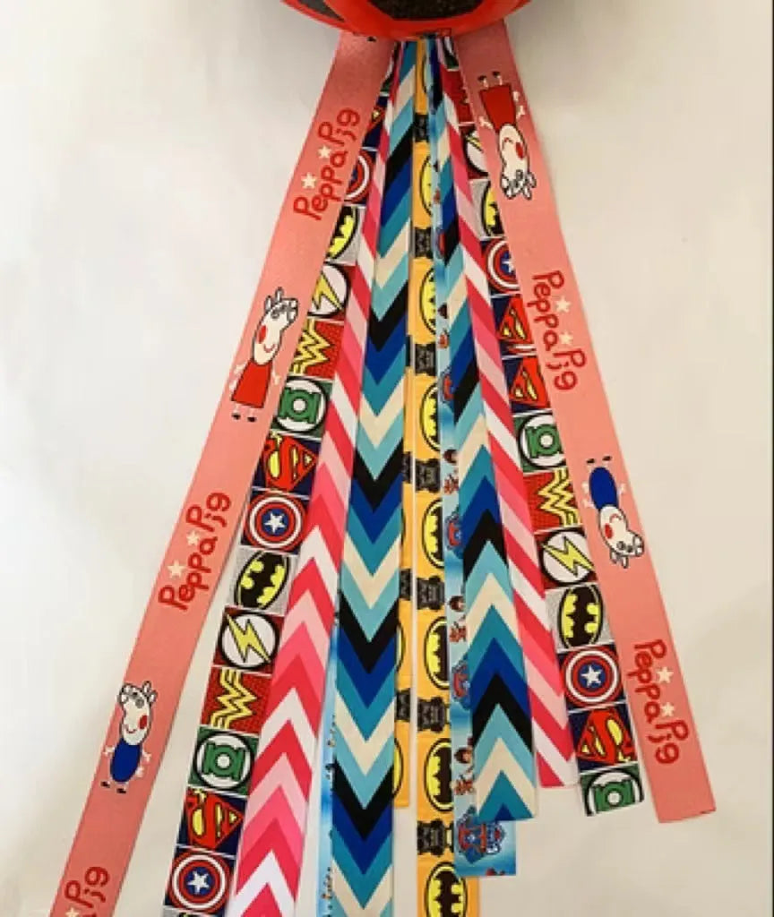 Colourful fabric helmet streamers for children's roller skating and ski helmets, shown in apricot, red, and grey.