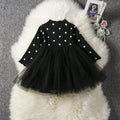 Baby girl wearing a long sleeve white lace tutu dress for a birthday or christening.