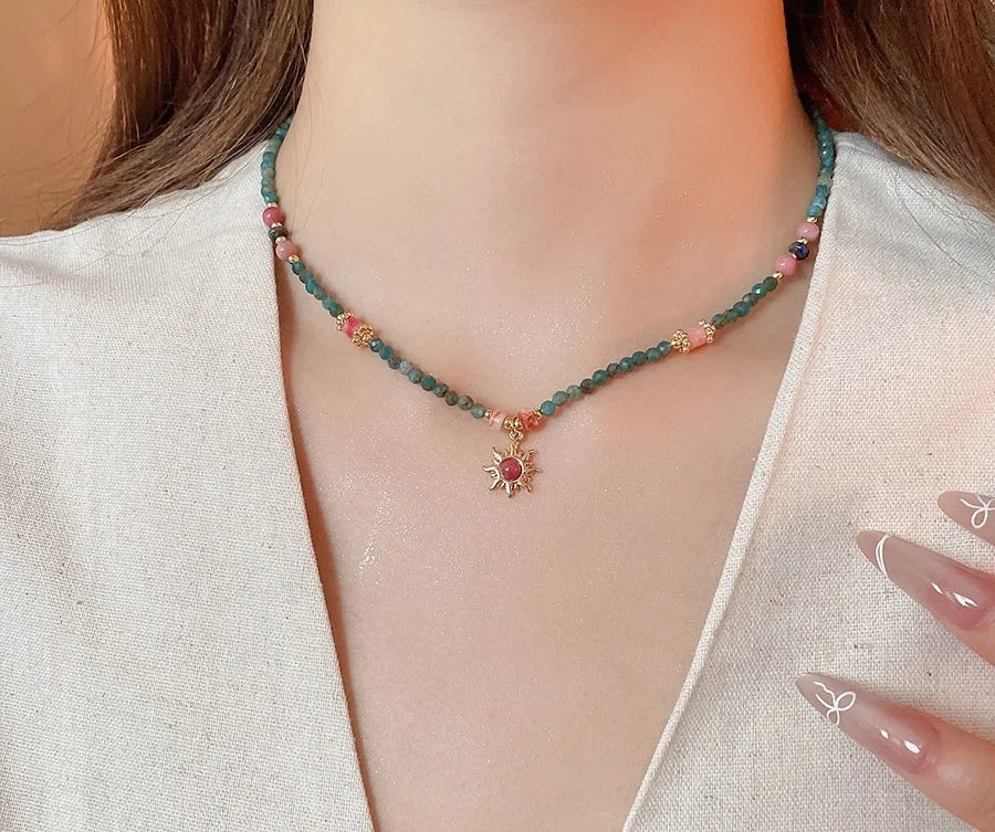 Freshwater pearl necklace with blue stone sun pendant on a gold-tone adjustable chain.