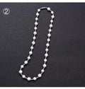 White freshwater pearl necklace with round bead chain and sterling silver platinum beads on a neutral background