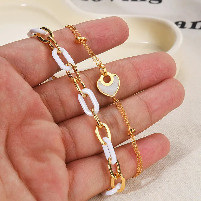 Close-up of a women's stainless steel bracelet featuring a double-layer heart charm with resin details.