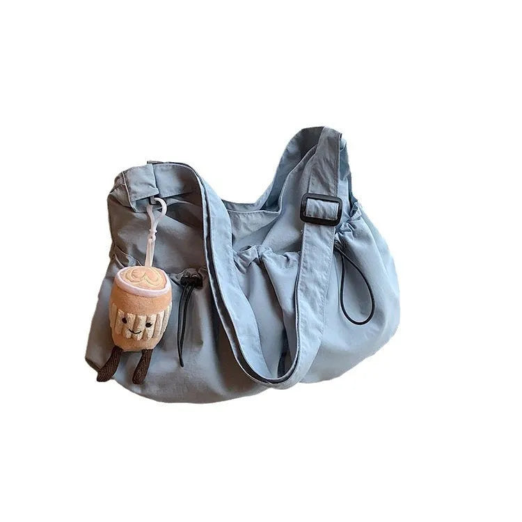 Pleated foldable polyester crossbody student bag in multiple colours showing split pocket and compact 35cm dimensions