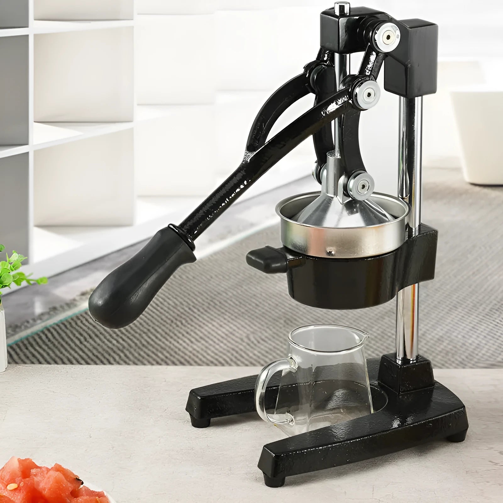 Black and white manual citrus juicer with cast iron base and stainless steel funnel, 40cm tall.