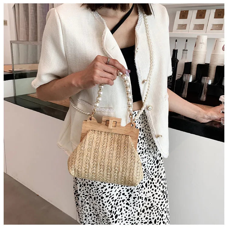 Women's woven straw shoulder bag with pearl chain detailing in horizontal square shape showing internal compartments