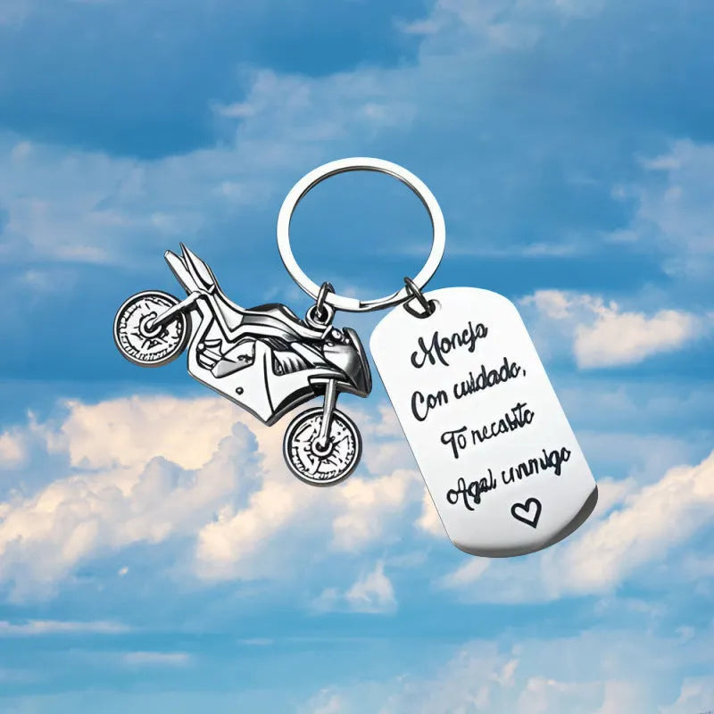 Stainless steel motorcycle keychain with a dark flannel storage pouch on a grey background.