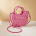 Woven straw beach bag in beige, peach skin lining, crossbody style, 24cm height, on a sandy beach