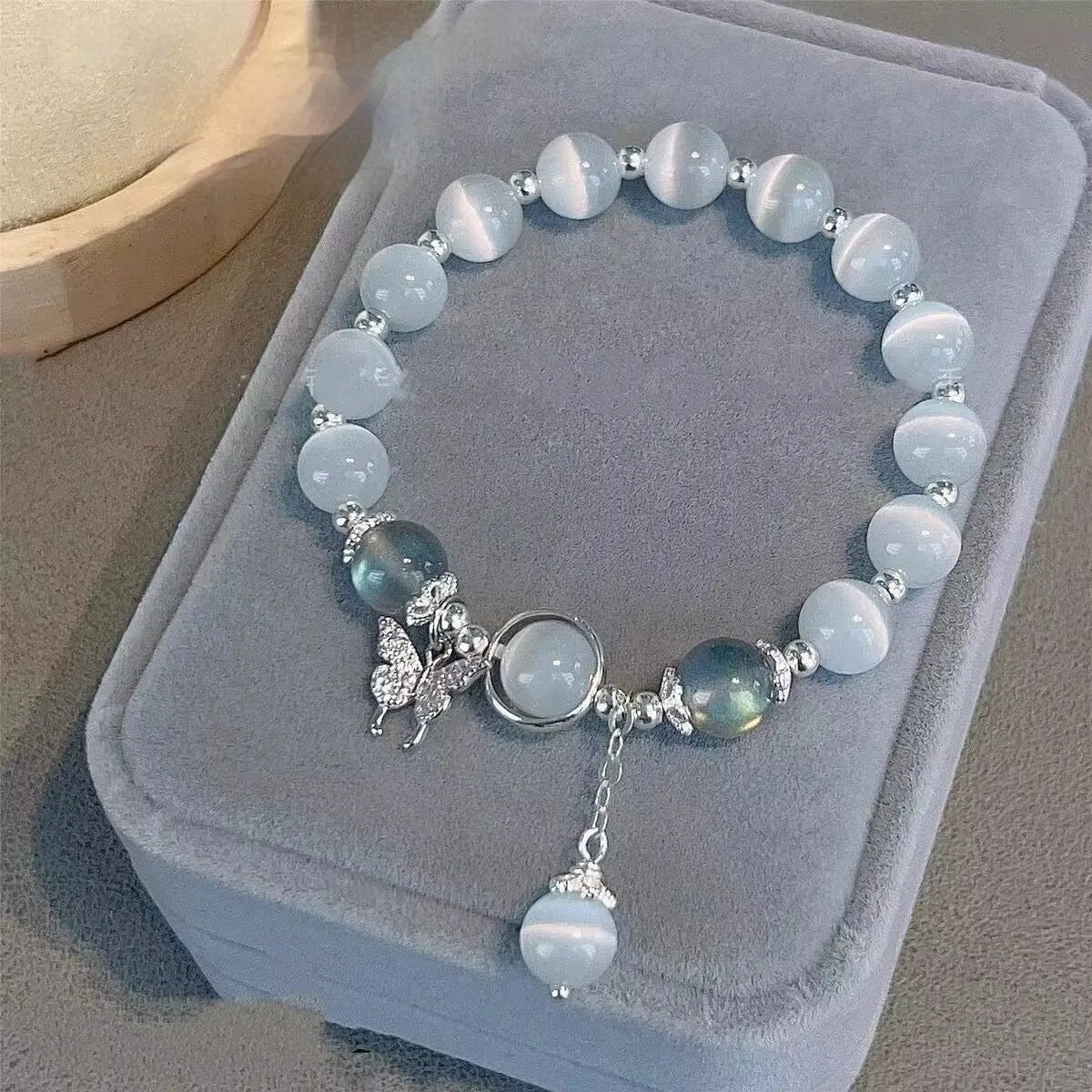 Close-up of a drop-shaped glass butterfly bracelet with round coloured beads on a wrist.