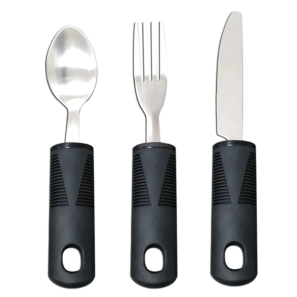 Stainless steel adaptive knife, fork, and spoon set with black rubber handles on a table.