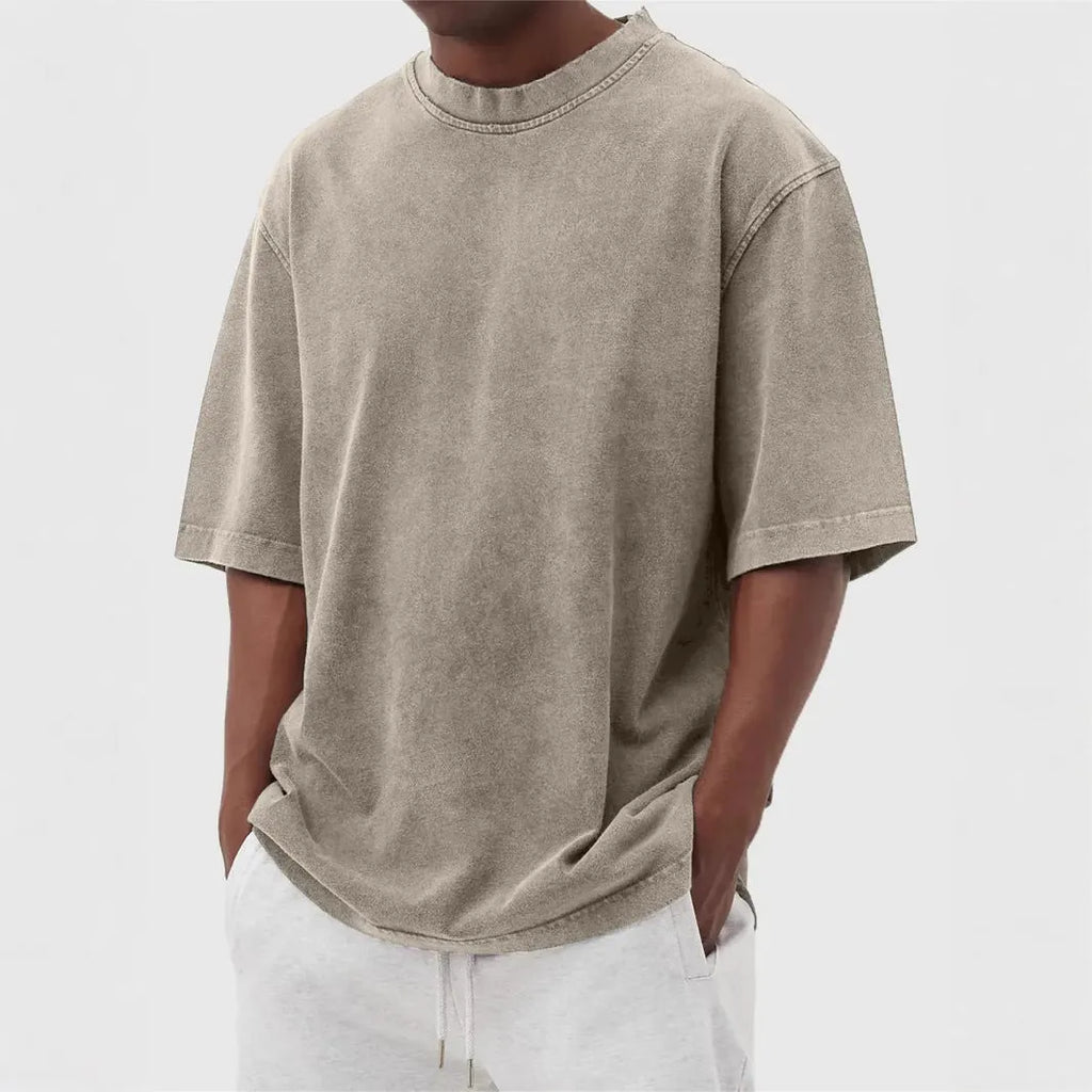 Man wearing a loose-fit, stone-washed polyester T-shirt in a solid colour with a distressed finish.