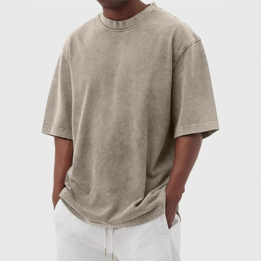 Man wearing a loose-fit, stone-washed polyester T-shirt in a solid colour with a distressed finish.