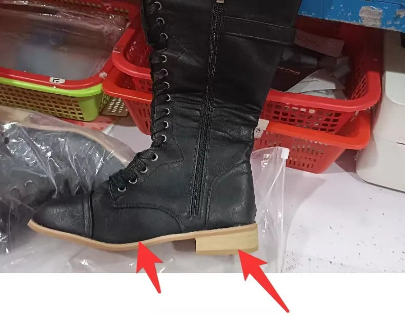 Women's black knee-high boots with a cross strap detail on the shaft, made of artificial PU leather.