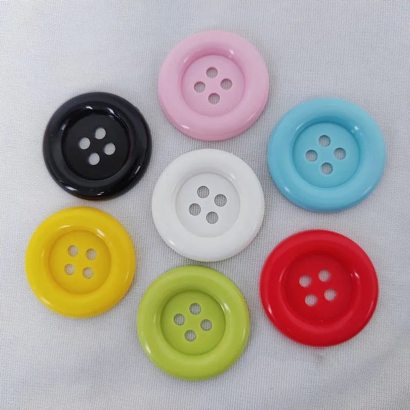 Assortment of oversized round plastic buttons in multiple colours with four stitching holes.