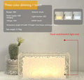 Clear acrylic geometric ice cube shaped night lamp glowing with multi-coloured LED light on a dark surface.