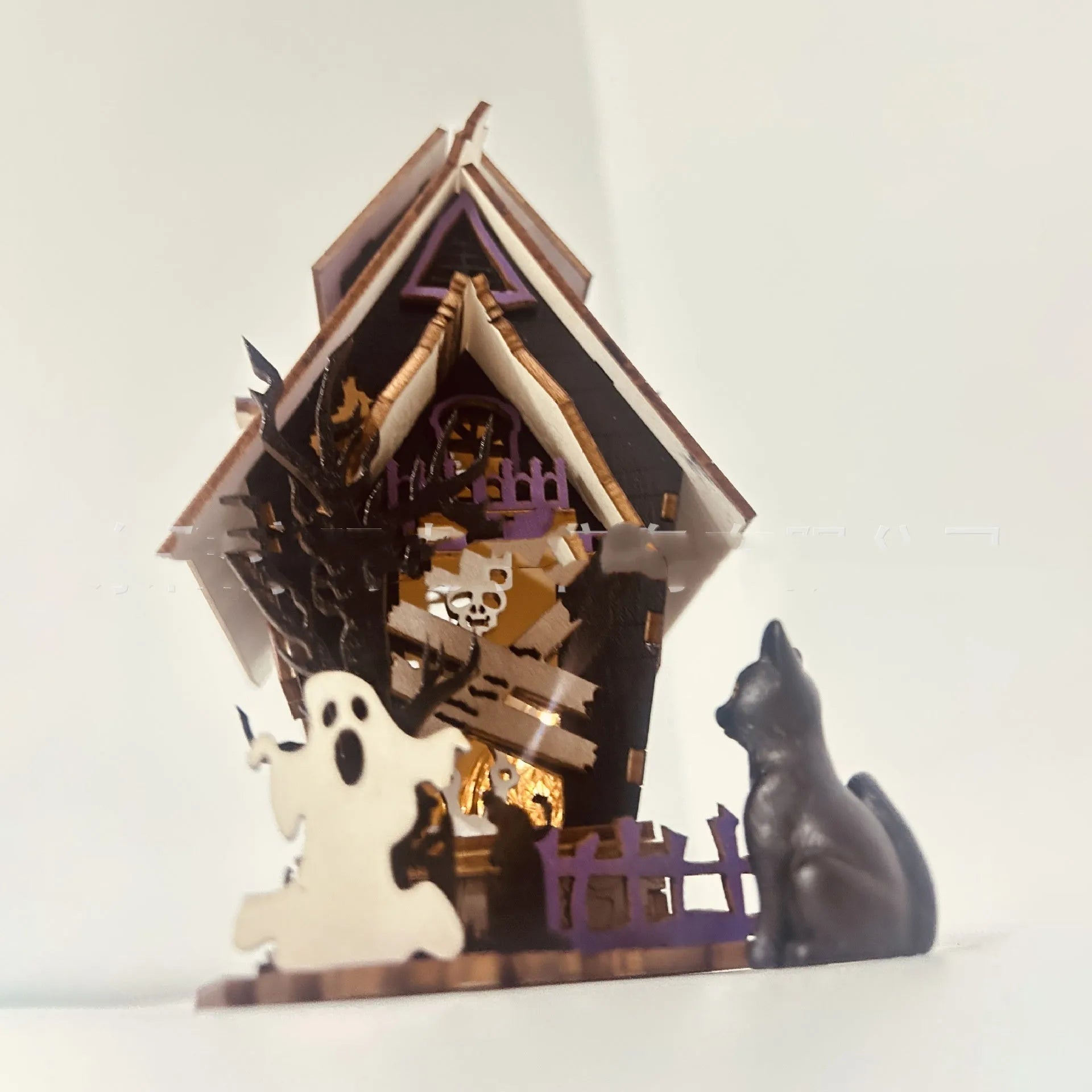 Unassembled DIY wooden haunted house Halloween decoration kit with glowing colour details.
