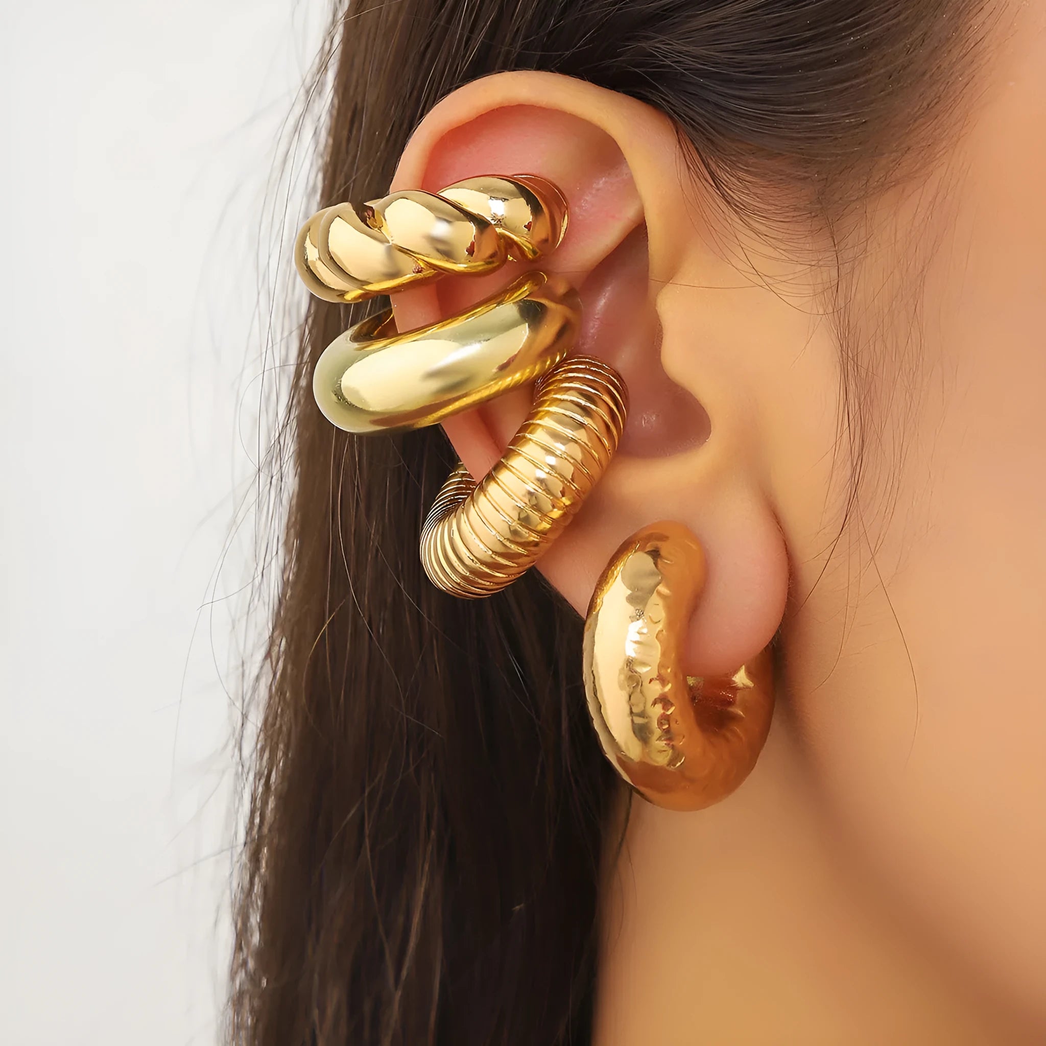 Set of four geometric gold and silver clip-on earrings for women on a flat surface.
