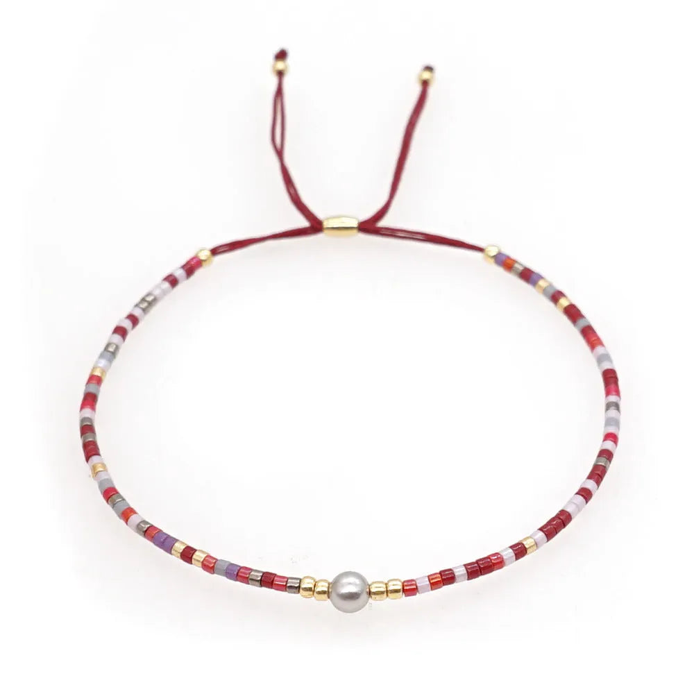 Women's handmade Bohemian bracelet with colourful glass beads in geometric shapes on a wrist.