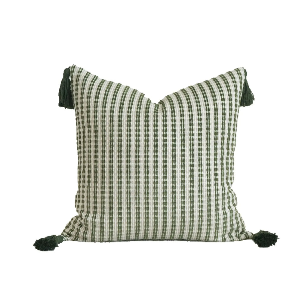 Green striped and botanical patterned hotel sample pillow with tassels on a bed display.