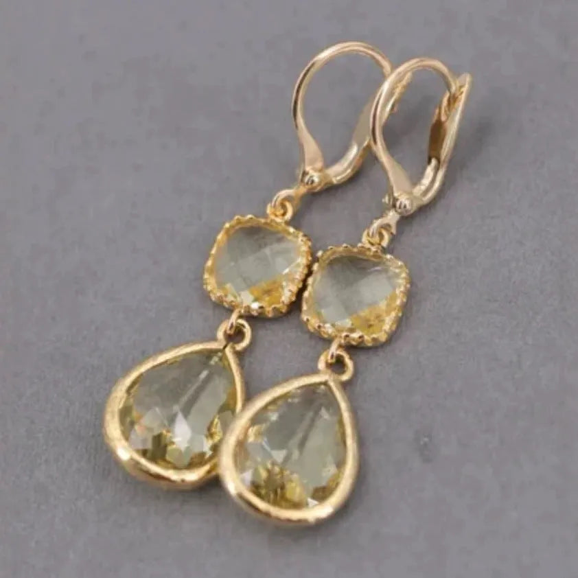 Gold geometric dangle earrings with a long fringe and water droplet design on a white background.