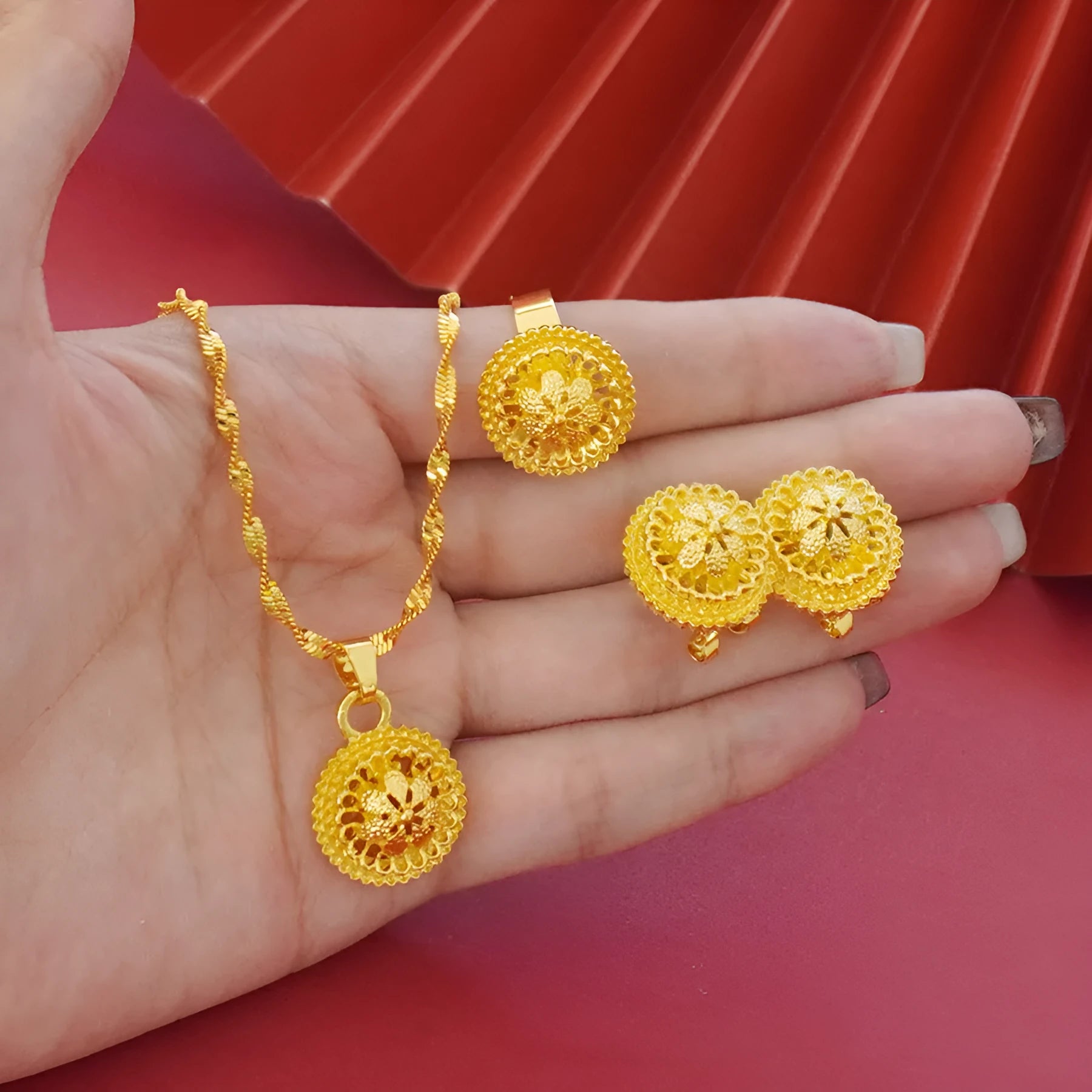 Gold-coloured three-piece jewellery set showing necklace with water wave chain, floral design earrings, and matching ring.