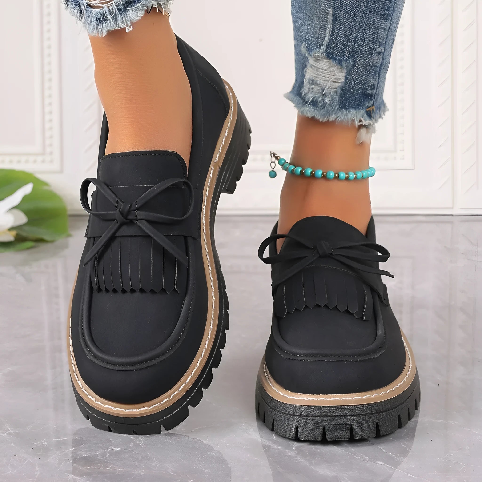 Women's black plus size loafers with a tassel and bowknot decoration and a chunky rubber sole.