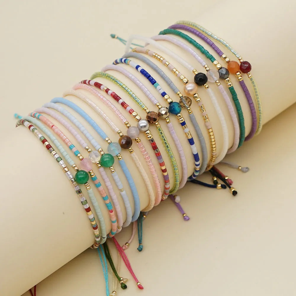 Women's handmade Bohemian bracelet with colourful glass beads in geometric shapes on a wrist.