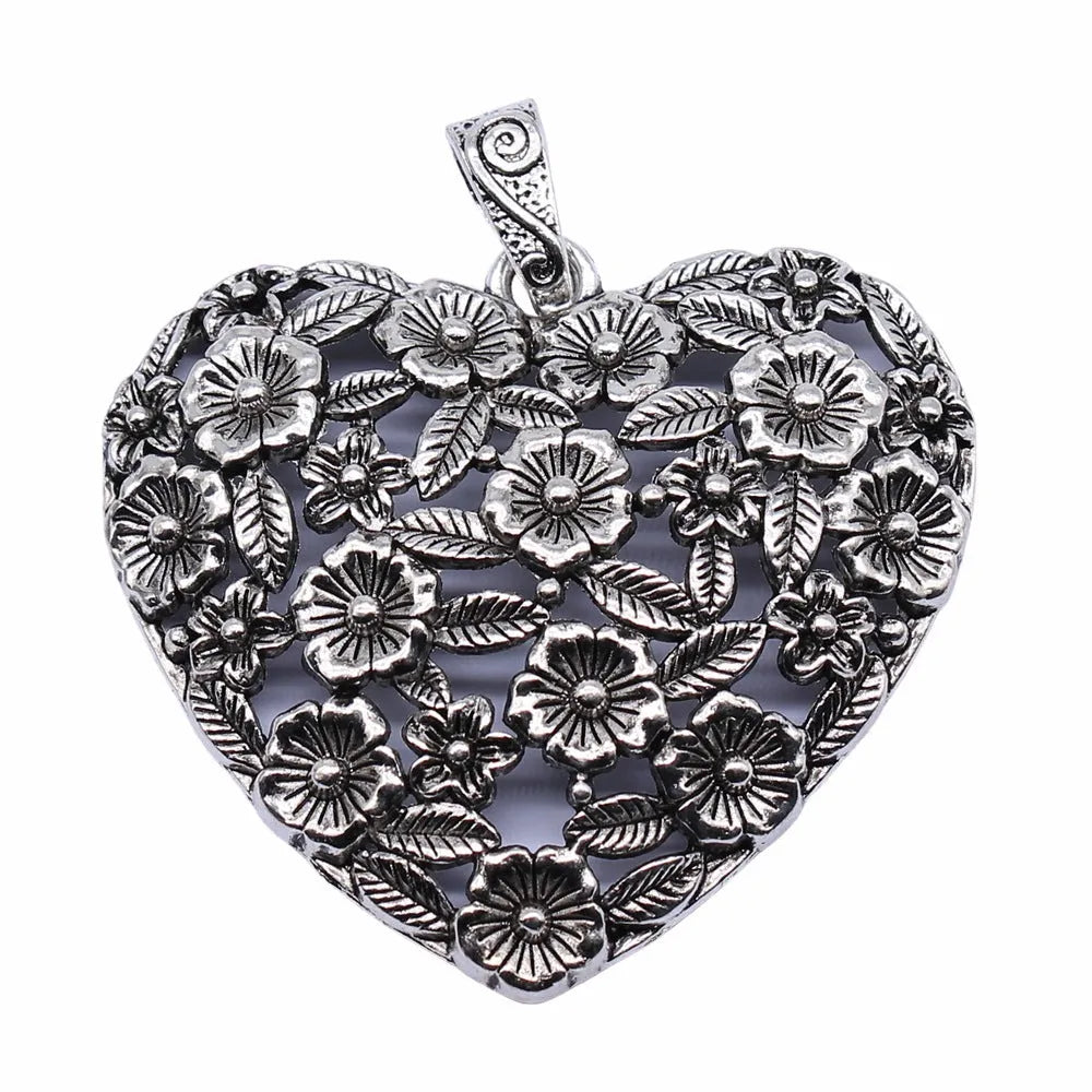 Close-up of a hollow flower love pendant in ancient silver colour, showing its detailed openwork design.