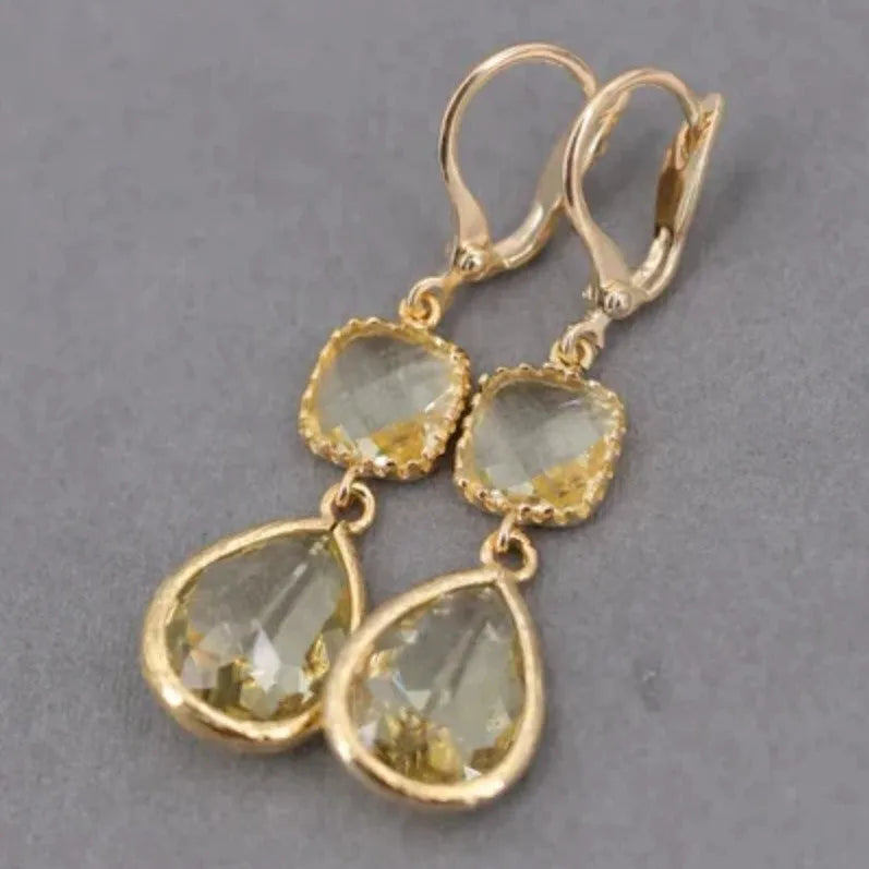 Gold geometric dangle earrings with a long fringe and water droplet design on a white background.